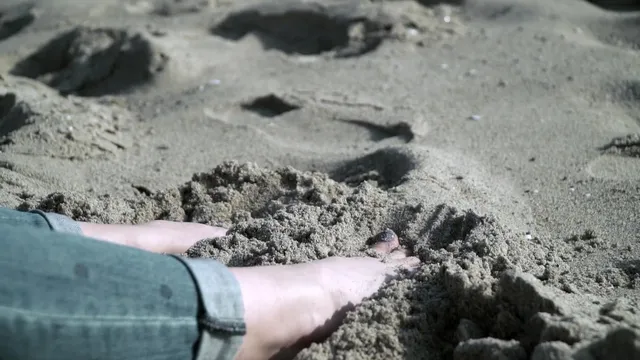 Elisha Cuthbert resting her bare feet in sand.