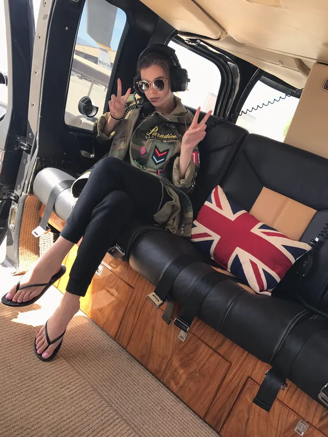 Hailee Steinfeld sitting in flip-flops inside a vehicle.
