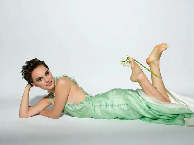 Natalie Portman lying barefoot in a green dress with feet raised.