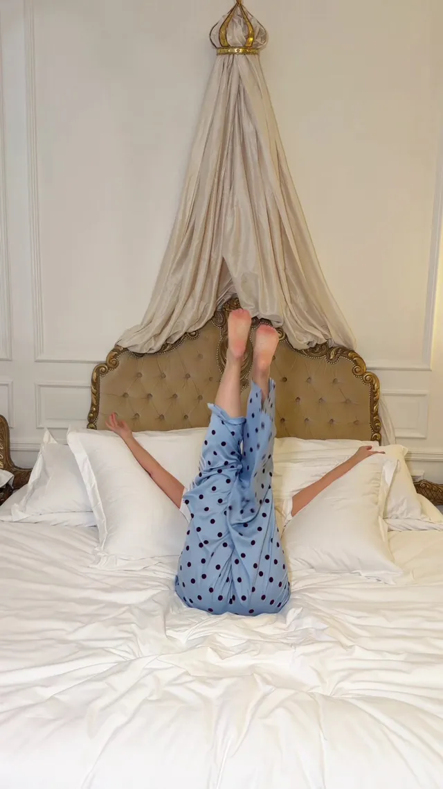 Kylie Minogue bare feet raised while relaxing on a white bed.