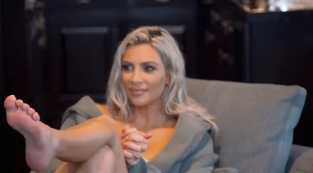 Kim Kardashian: seated with a bare foot extended toward the camera.