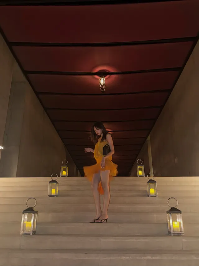 Lisa (Lalisa Manobal) posing in pale heels and a flowing yellow outfit in a hallway.