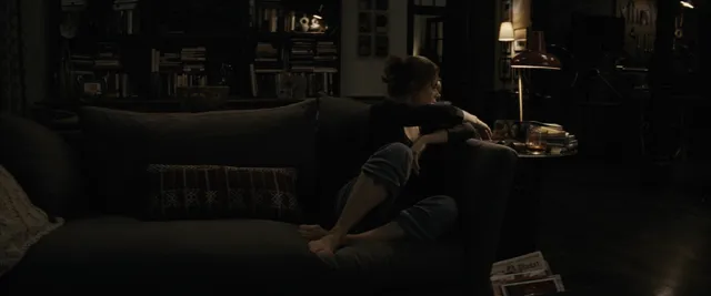 Amy Adams sitting on a sofa during a dark screen scene.