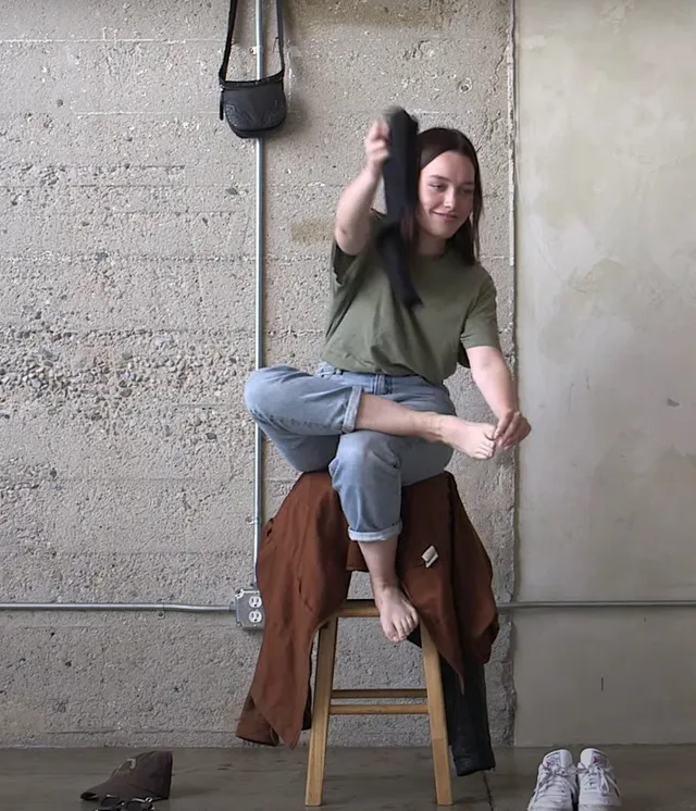 Victoria Pedretti posing on a stool in a T-shirt and jeans.