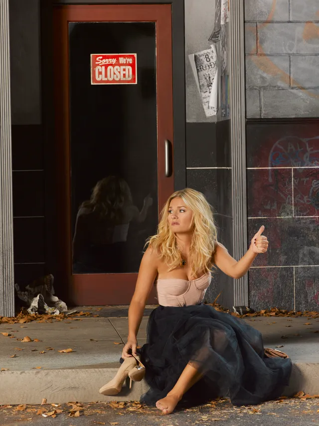 Elisha Cuthbert sitting barefoot on steps beside a pair of heels.