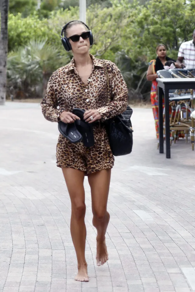 Nina Agdal standing outdoors in flat shoes and a leopard-print shirt dress.
