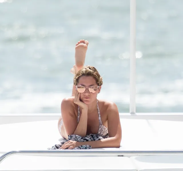 Ashley Tisdale lying on a boat with a bare foot raised.
