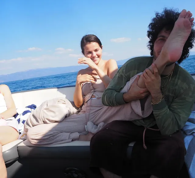 Selena Gomez: reclining on a boat with friends and a bare foot raised.