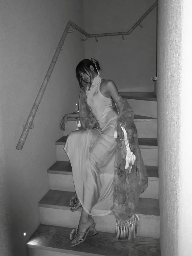 Lisa (Lalisa Manobal) walking down a staircase in metallic heels and a long pale dress.