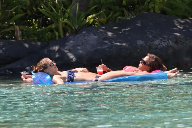 Alex Morgan floating barefoot in a swimming pool beside a companion.