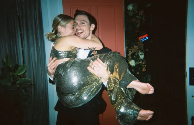 Hilary Duff being carried indoors in a green outfit with bare feet extended.