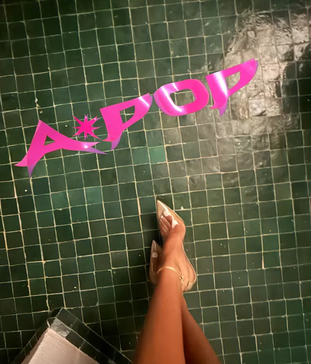 Tyla showing pale heels beside a tiled wall.