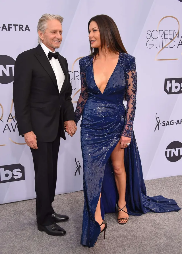 Catherine Zeta-Jones posing at an awards event in a blue gown.