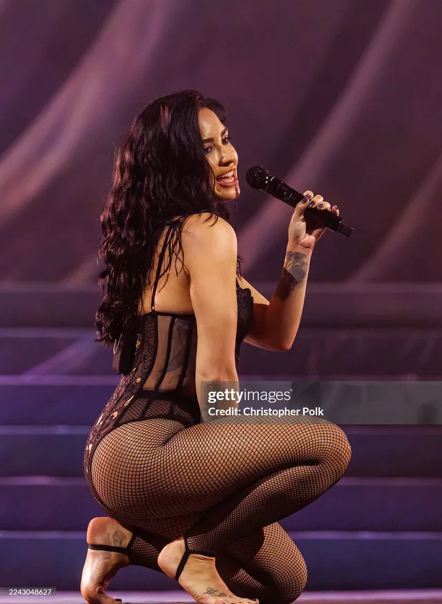 Demi Lovato performing on stage in black heels.