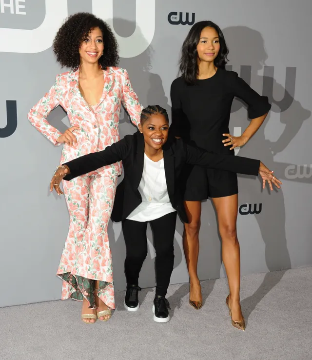 Samantha Logan posing with fellow performers in a floral suit and gold heels.