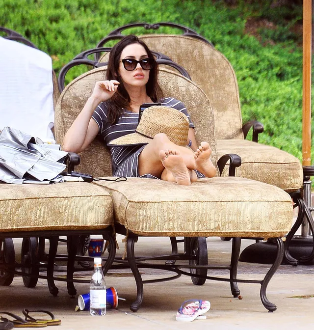 Megan Fox: reclining barefoot on a woven outdoor chair.
