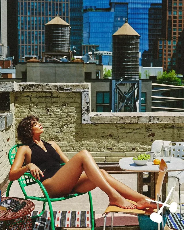 Taylor Hill reclining barefoot on an outdoor rooftop chair.