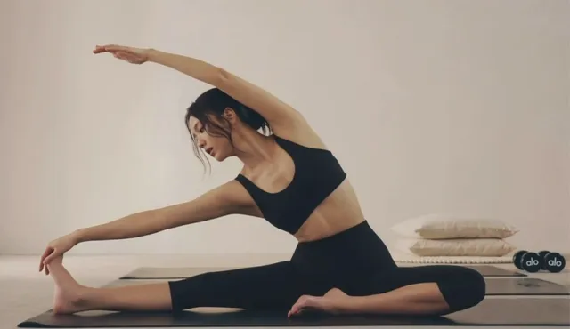 Jisoo stretching barefoot sideways on an exercise mat.