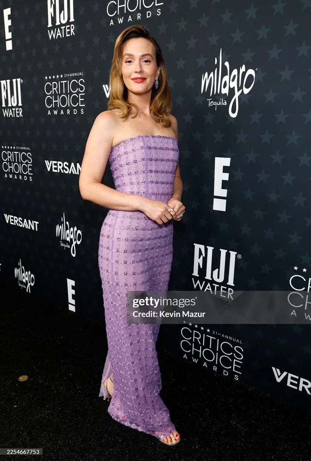 Leighton Meester posing on a carpet in a purple dress.