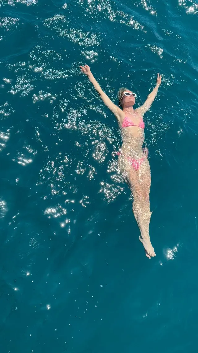 Paris Hilton swimming in blue water.