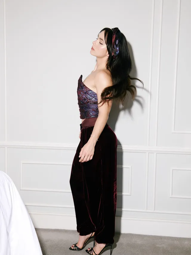 Clara Galle posing in a dark skirt outfit and open-toe heels indoors.