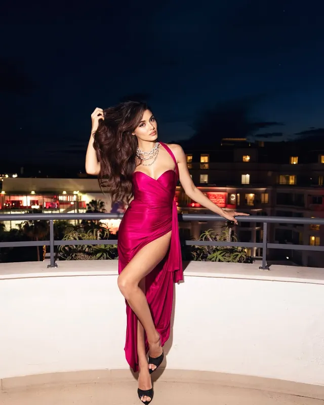 Hande Erçel posing in a pink gown and black heels.