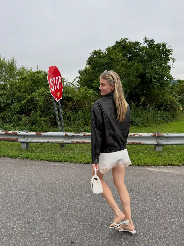 Eugenie Bouchard walking outdoors in flat sandals and pale shorts.