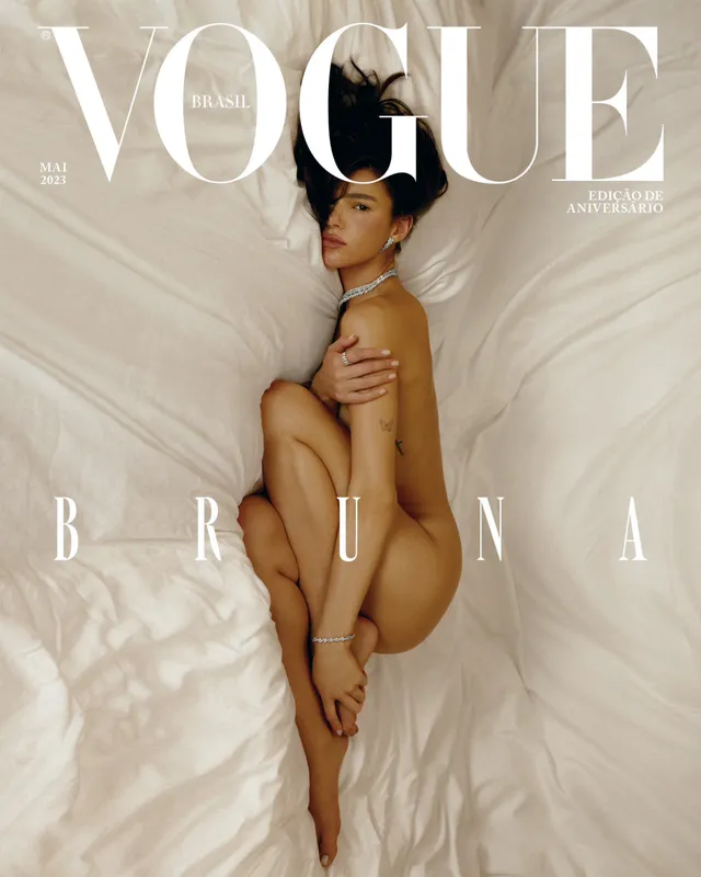 Bruna Marquezine reclining barefoot on pale bedding for a Vogue cover.