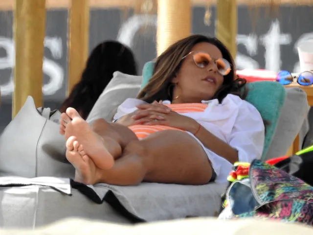 Eva Longoria reclining on a beach lounger in sunglasses.