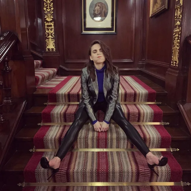 Hayley Atwell sitting on carpeted stairs in a patterned outfit.
