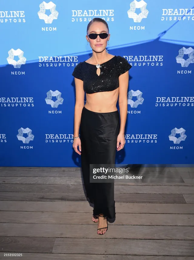 Maika Monroe wearing a black outfit and pale heels at an event.