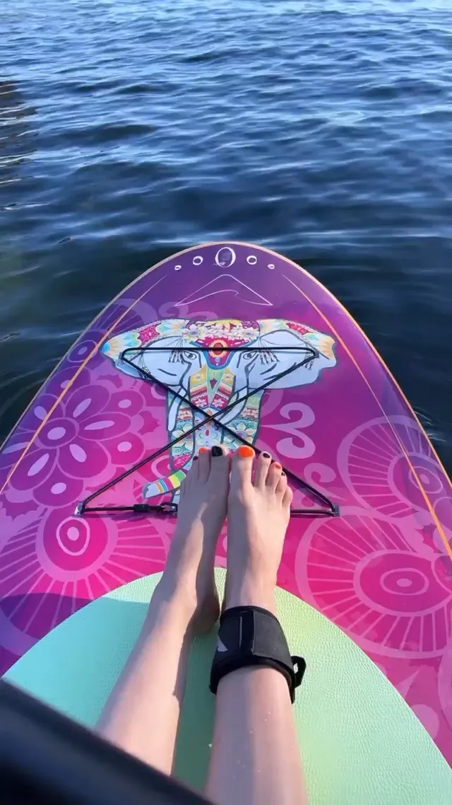 Avril Lavigne resting bare feet on a colourful paddleboard.