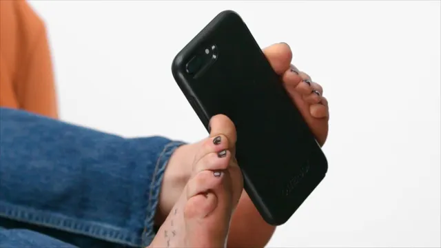 Dakota Johnson holding a phone beside a sandal-clad foot.