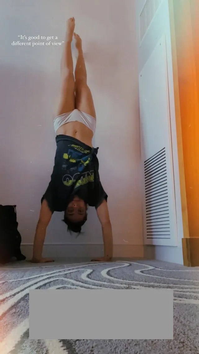 María Gabriela de Faría performing a barefoot handstand against a wall.