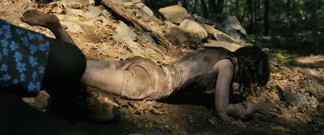 Sophie Thatcher lying on a woodland floor in an outdoor film scene.