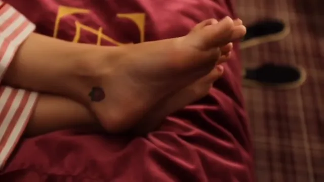Katy Perry raising bare soles while reclining on a bed.