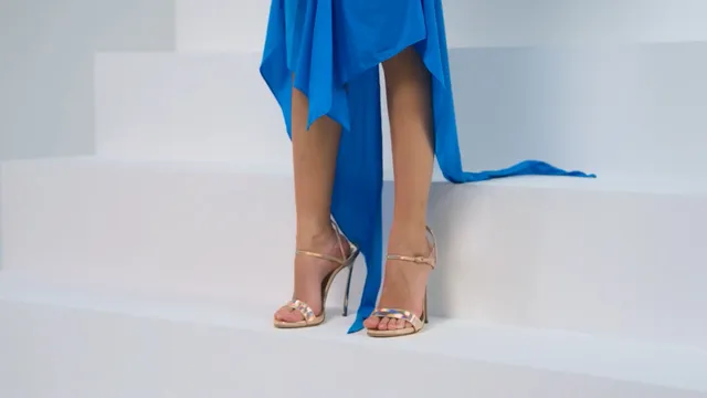 Nico Parker wearing metallic heels beneath a blue dress on studio steps.