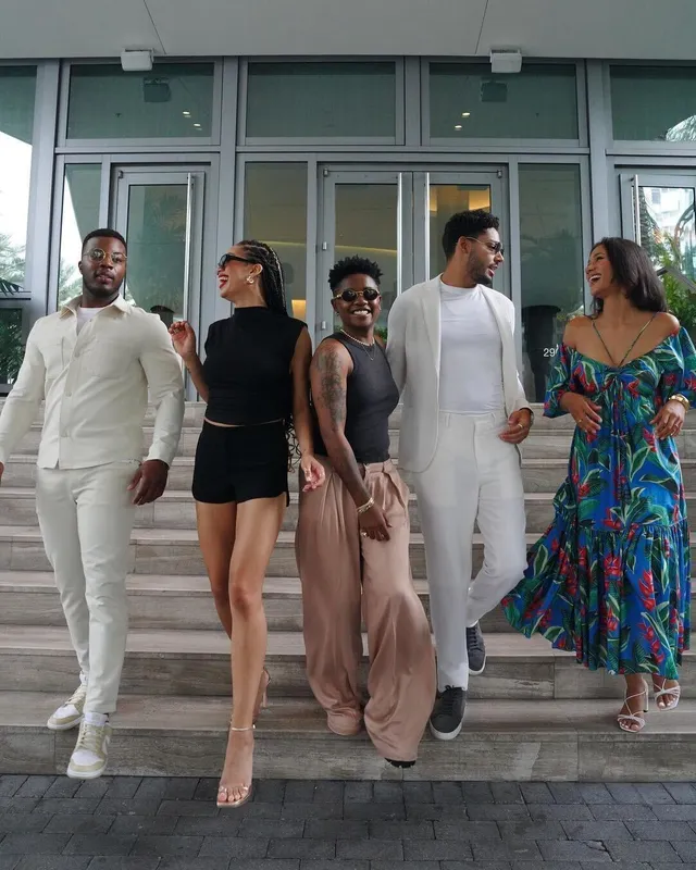 Samantha Logan posing with a group in a black outfit and pale heels.