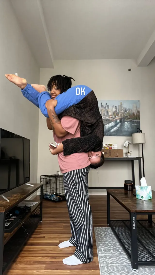 Isabela Merced being lifted by a man with her bare feet raised.