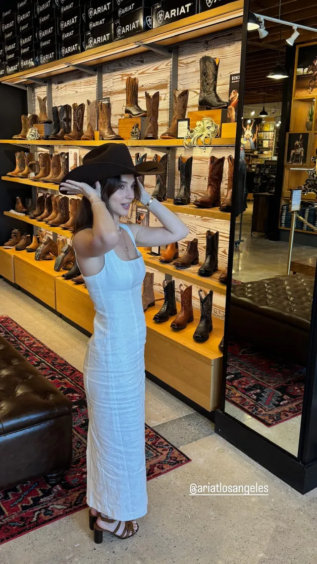 Adelaide Kane posing in a shop in a pale outfit.