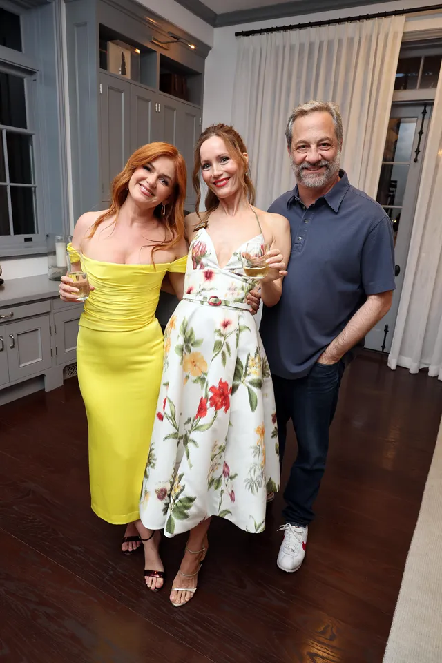 Isla Fisher posing with companions in a yellow dress.