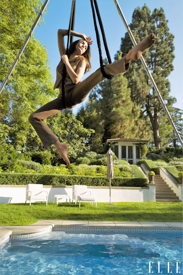 Angelina Jolie swinging above a pool with one leg extended.