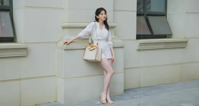Han So-hee posing outdoors in a pale outfit and heels.
