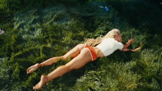 Zara Larsson lying barefoot on grass.