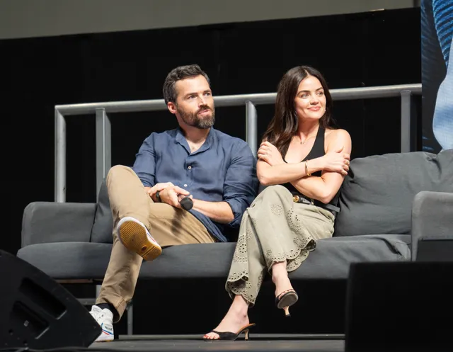 Lucy Hale sitting onstage beside a fellow panelist.