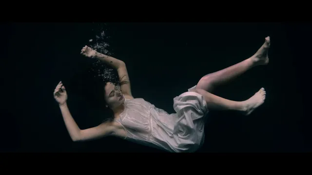 Emily Alyn Lind shown floating underwater in a pale dress in a scene.