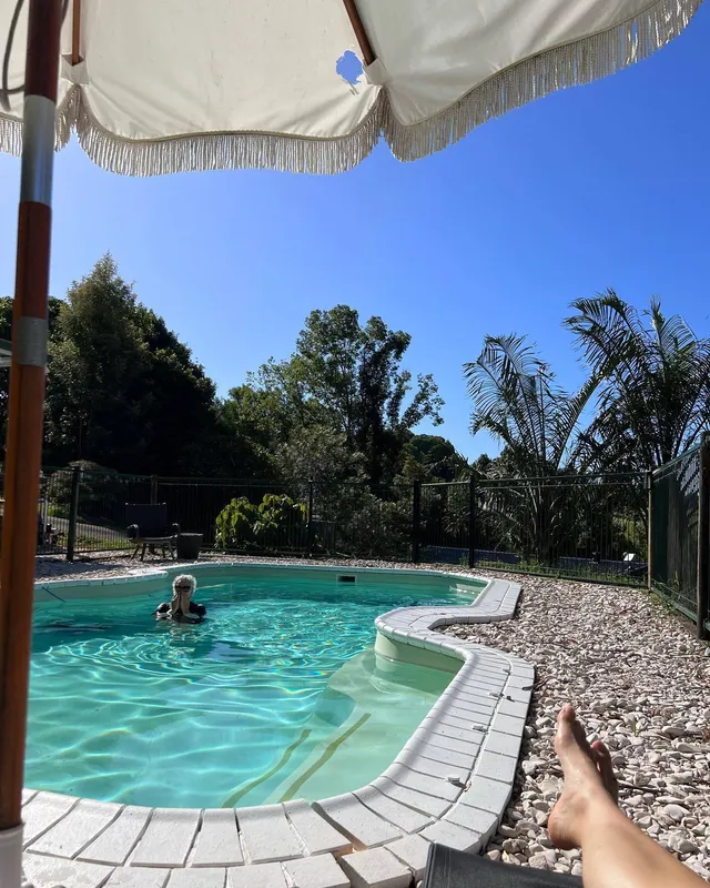 Maia Mitchell resting a bare foot beside a swimming pool.