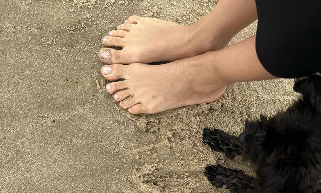 Irina Shayk bare feet on textured ground beside a dog.