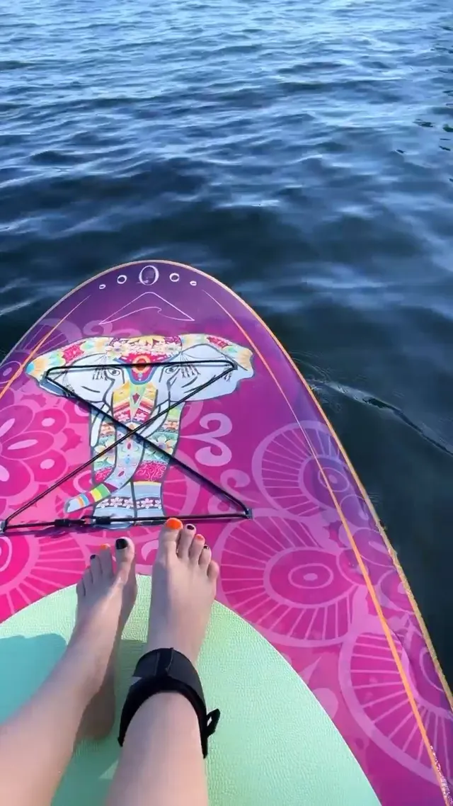 Avril Lavigne resting bare feet on a colourful paddleboard.