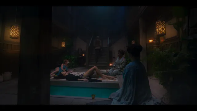 Anya Chalotra reclining beside a pool in an indoor film scene.